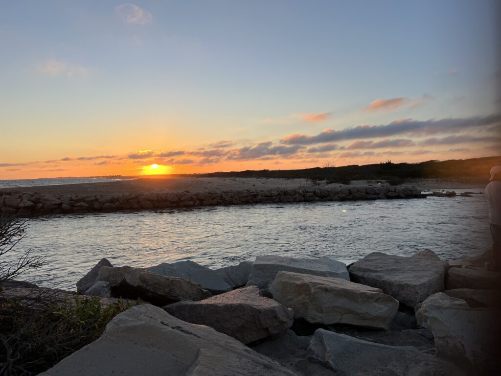 a body of water with rocks and a sunset in the background (MyCoast AI)