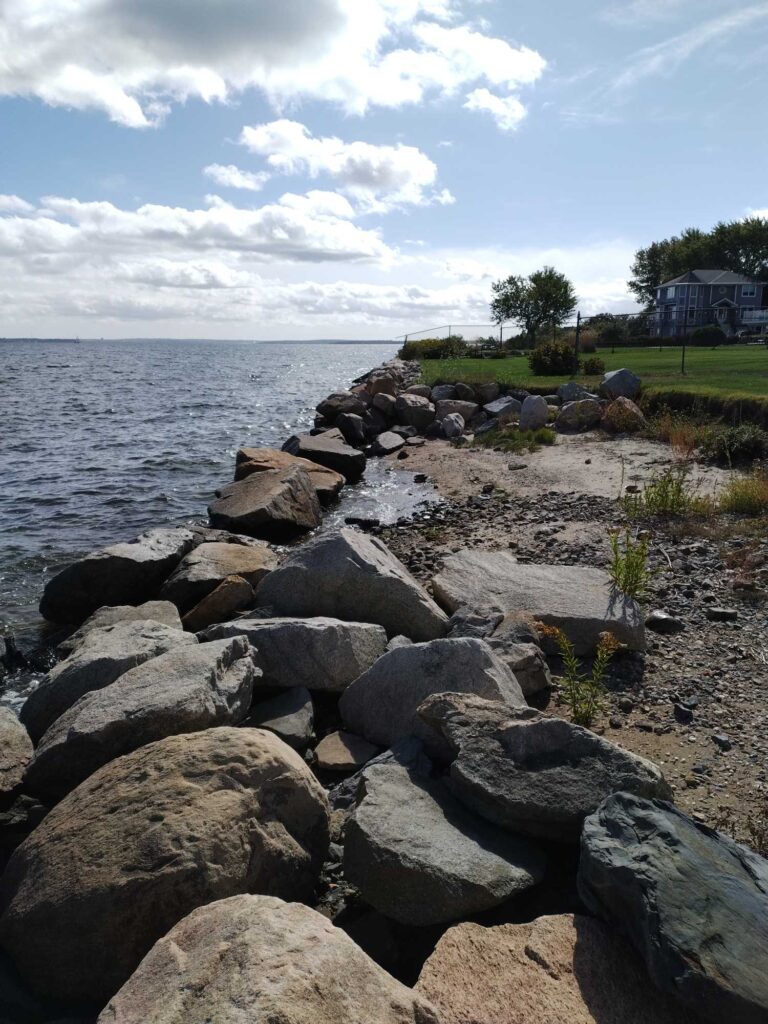 a rocky beach with a house in the background (MyCoast AI)