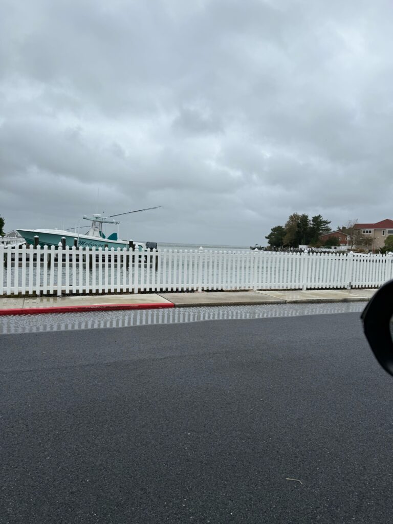a road with a white fence and a white building with a red railing (MyCoast AI)