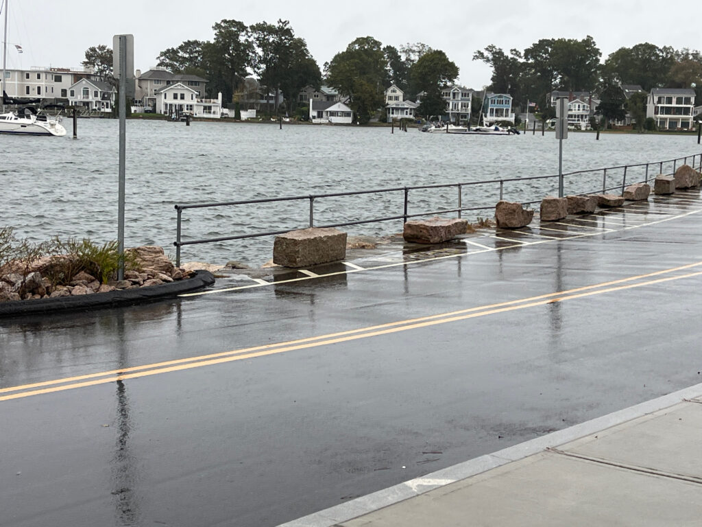 a road with a railing and a body of water with houses in the background (MyCoast AI)