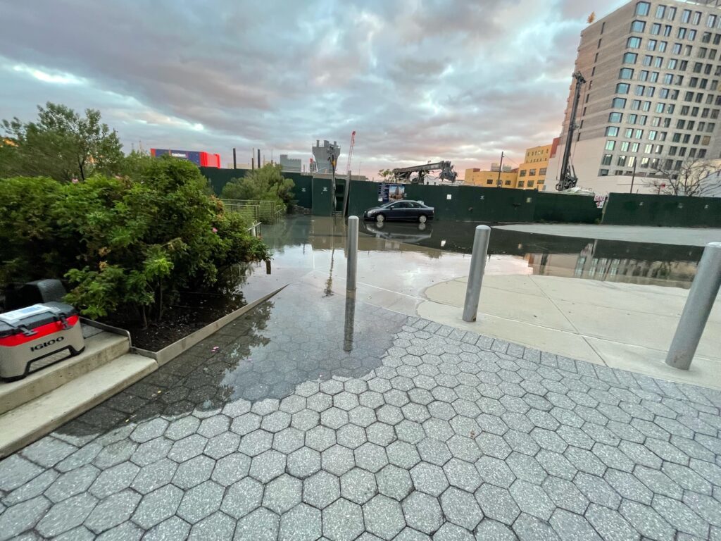 a stone walkway with cars parked on it and buildings in the background (MyCoast AI)