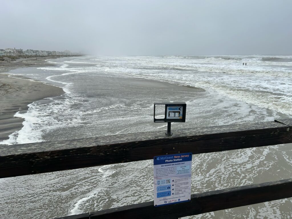 a sign on a railing overlooking a beach (MyCoast AI)