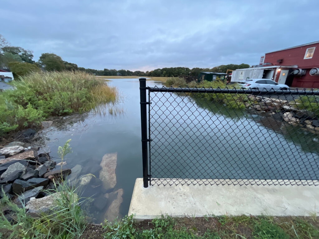a body of water with a fence and a building in the background (MyCoast AI)