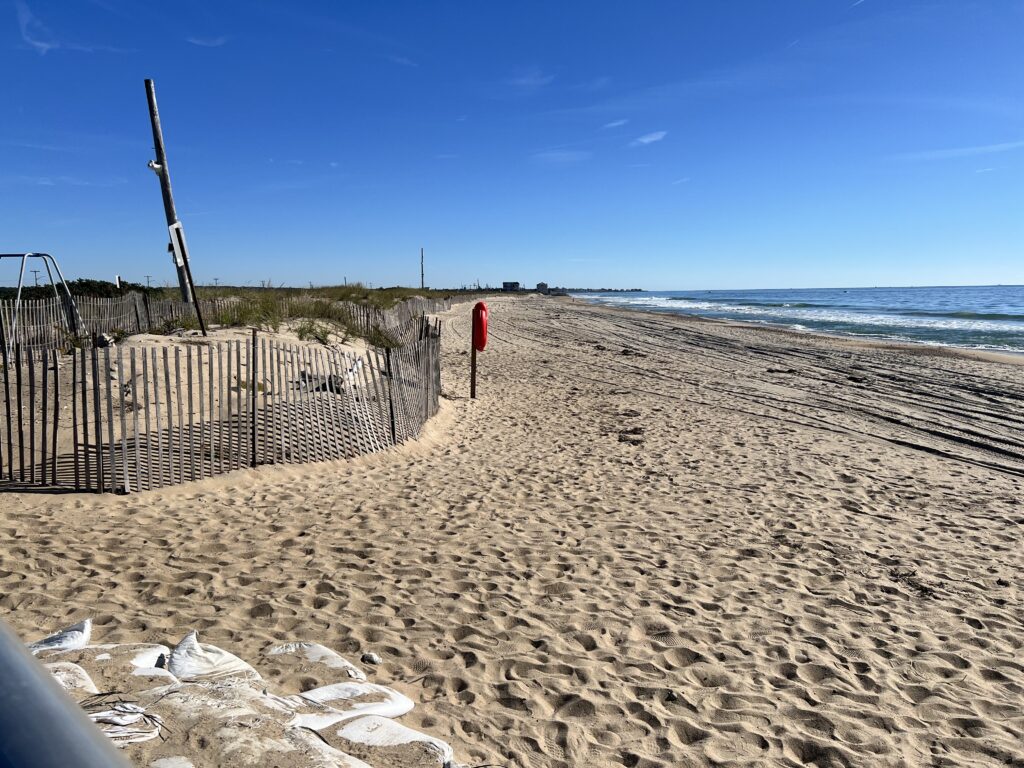 a sandy beach with a fence and a metal gate (MyCoast AI)