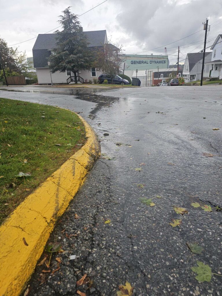 a wet street with a yellow curb and a building (MyCoast AI)
