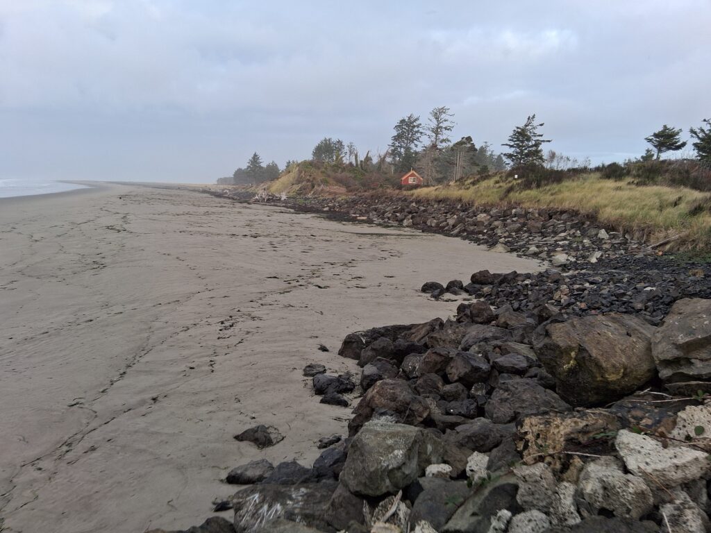 a rocky beach with a house in the distance (MyCoast AI)