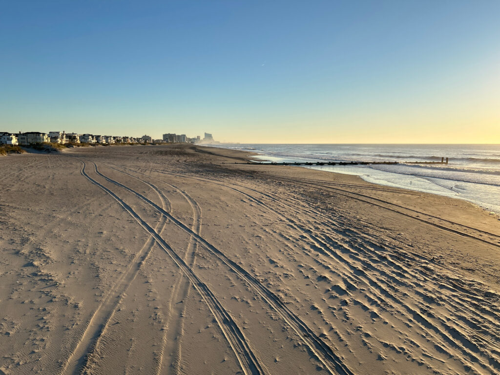 a long straight road with tracks on the sand by the water (MyCoast AI)