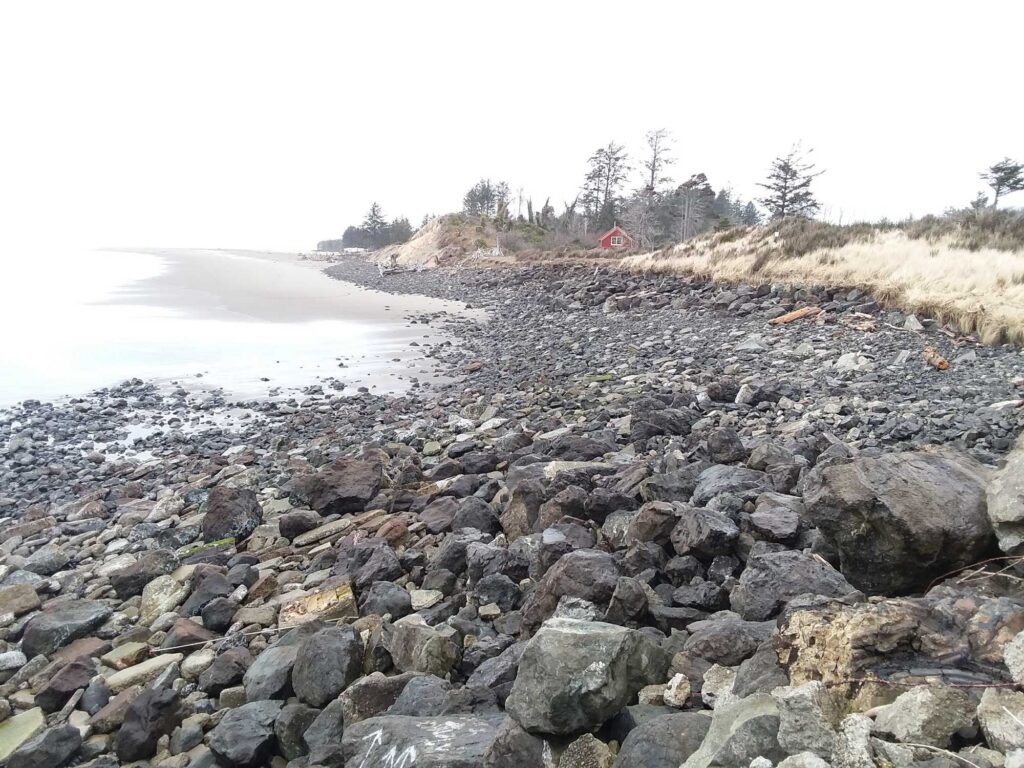 a rocky beach with a red tent in the distance (MyCoast AI)