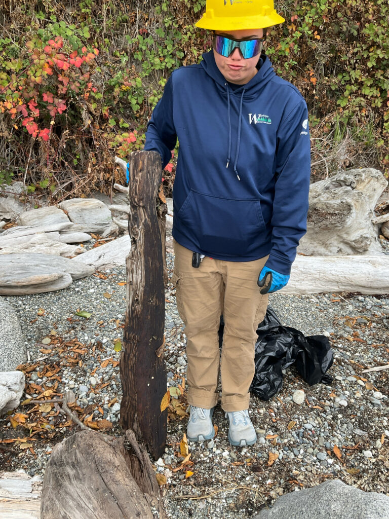 a man wearing a hard hat and gloves standing next to a tree stump (MyCoast AI)