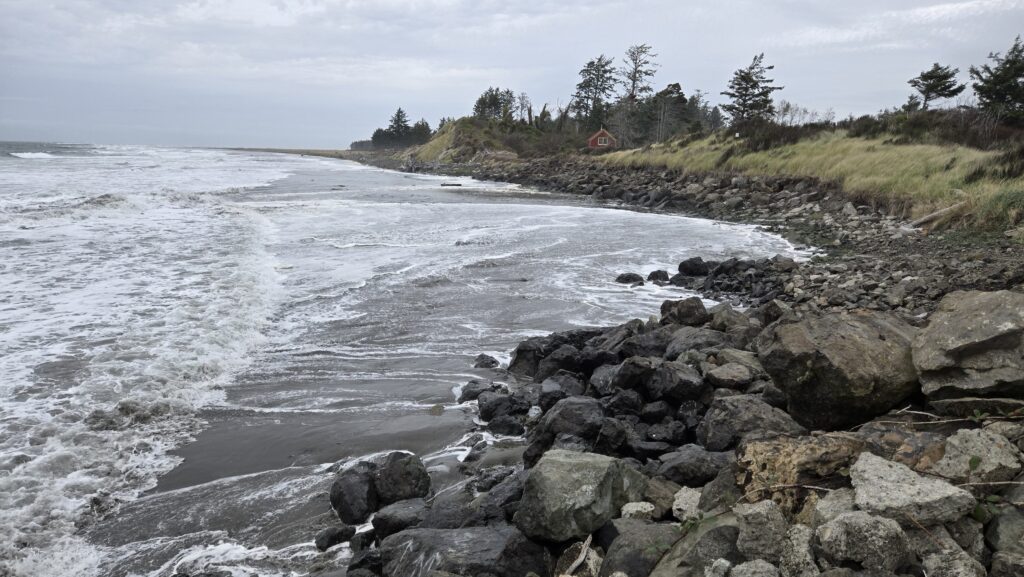 a rocky beach with a house in the background (MyCoast AI)