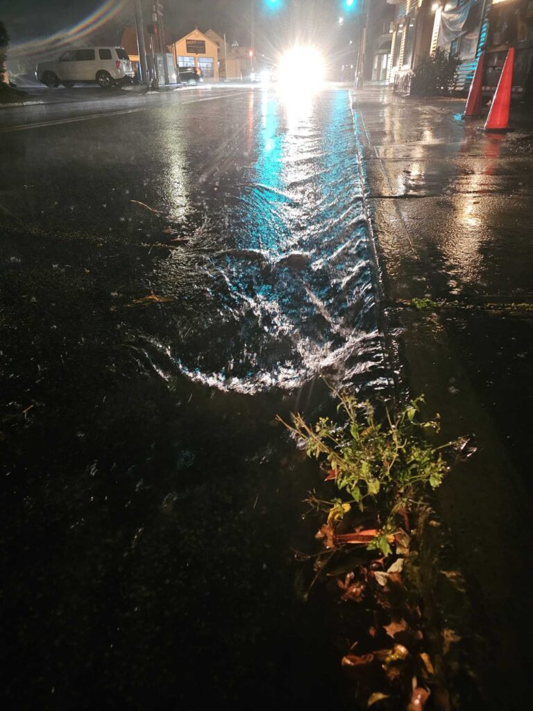 a street with a puddle of water and a car on it (MyCoast AI)