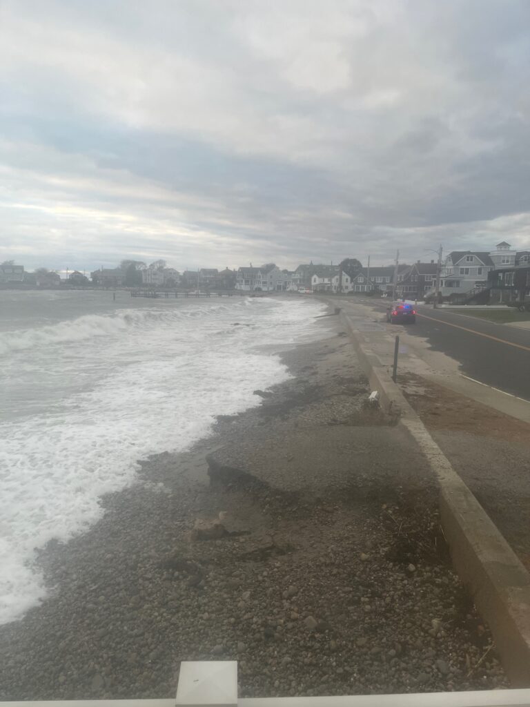 a road next to a body of water with buildings in the background (MyCoast AI)