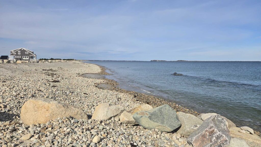 a rocky beach with a house in the distance (MyCoast AI)