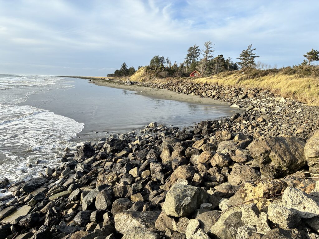 a rocky beach with a house in the distance (MyCoast AI)