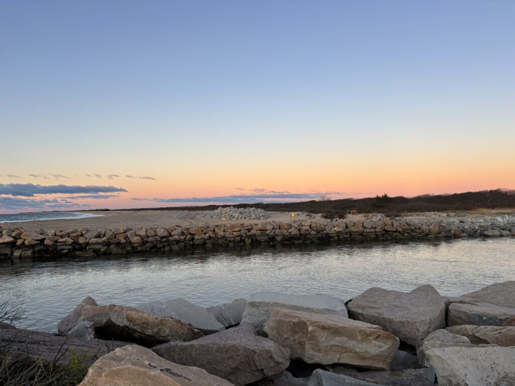 a body of water with rocks in it and a sunset in the background (MyCoast AI)