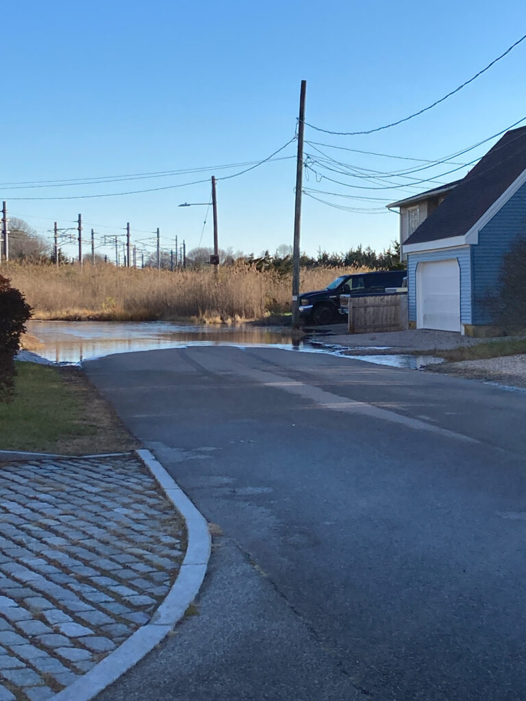 a road with a puddle on the side and a house on the side (MyCoast AI)