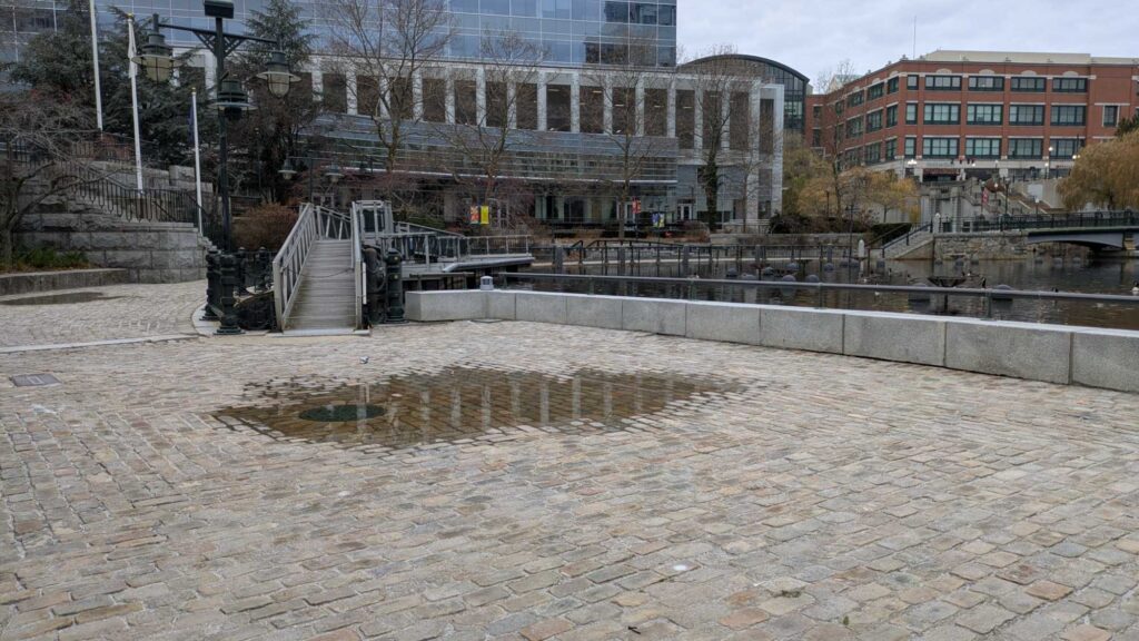 a courtyard with a fountain and buildings in the background (MyCoast AI)