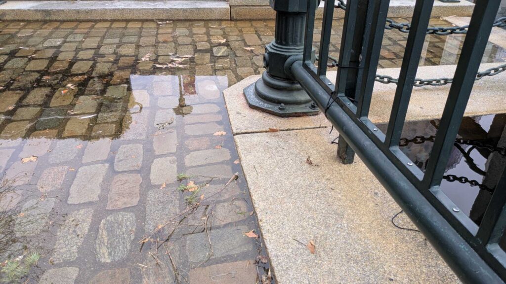 a metal railing on a brick sidewalk (MyCoast AI)