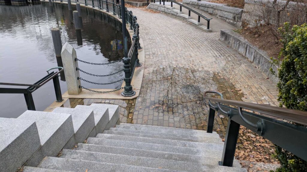 a stone walkway with railings and a body of water (MyCoast AI)