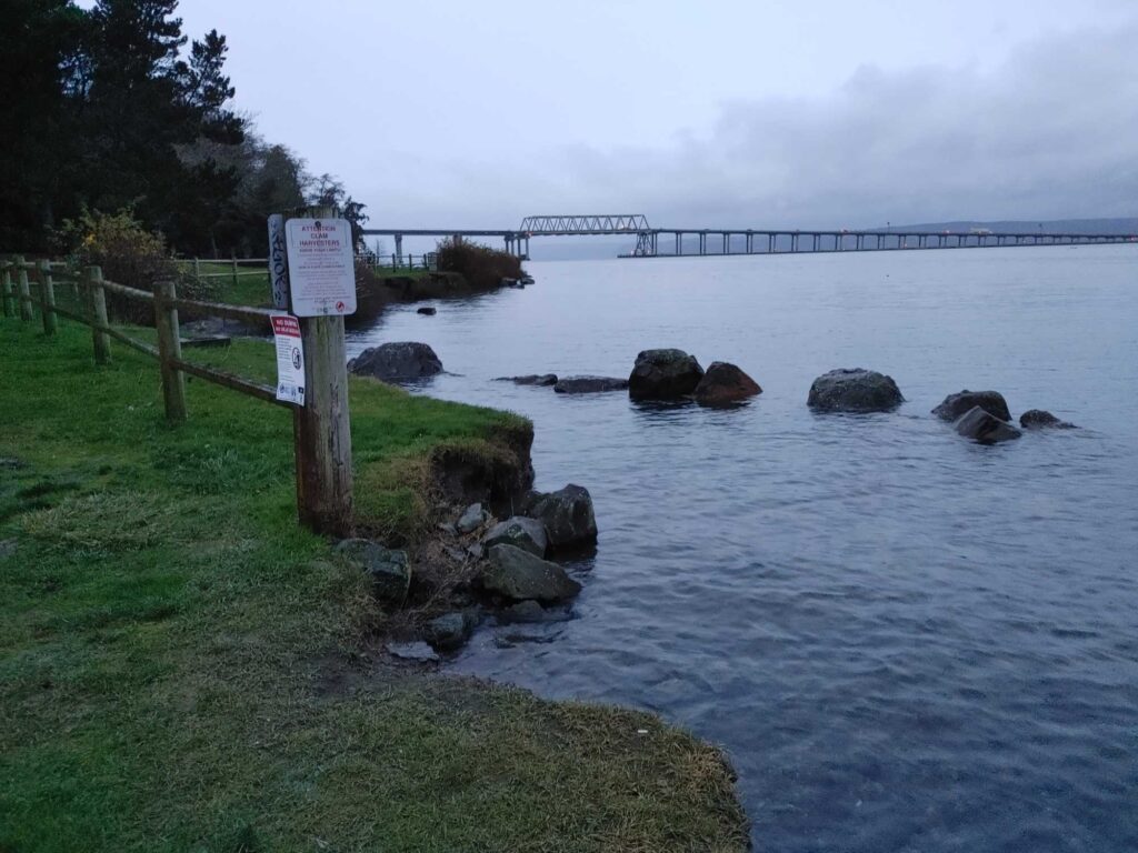 a body of water with rocks and a bridge in the background (MyCoast AI)