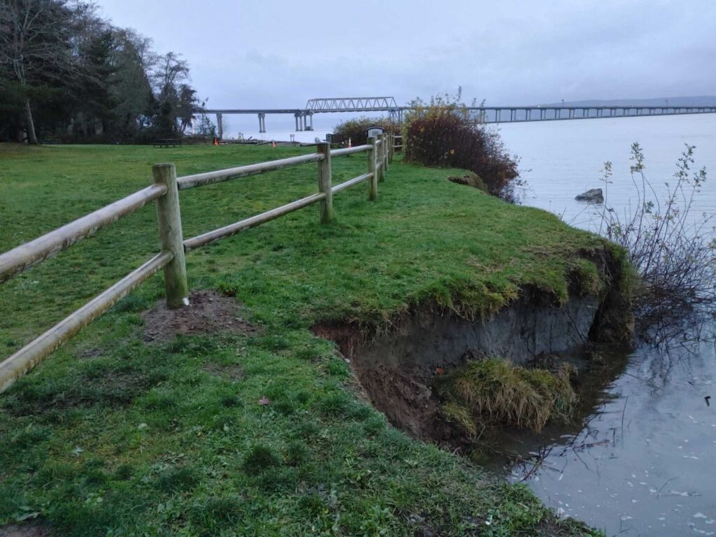 a wooden fence on a grassy hill by a body of water (MyCoast AI)