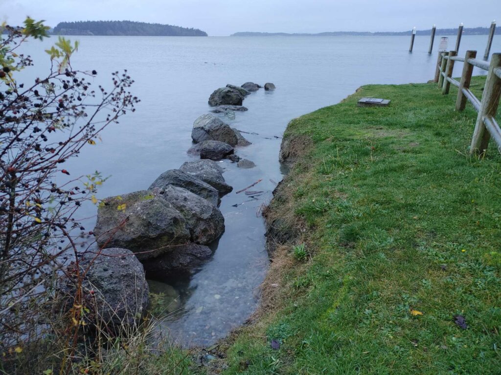 a rocky beach with a fence and a body of water (MyCoast AI)