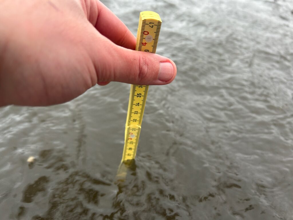 a hand holding a yellow measuring tape (MyCoast AI)