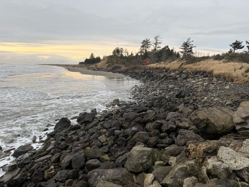 a rocky beach with a house in the distance (MyCoast AI)