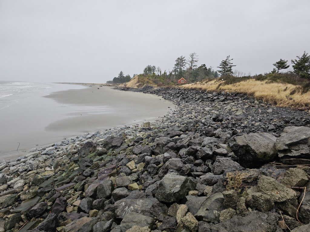 a rocky beach with a house in the distance (MyCoast AI)