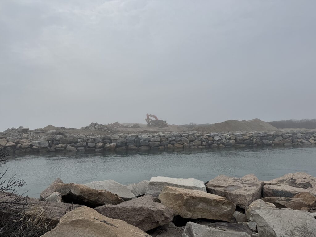 a rocky beach with a boat in the distance (MyCoast AI)