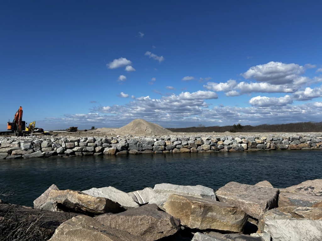a rocky beach with a body of water and a hill in the background (MyCoast AI)
