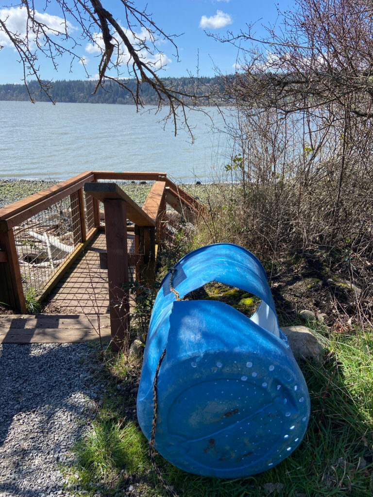 a blue barrel next to a wooden bridge over a body of water (MyCoast AI)