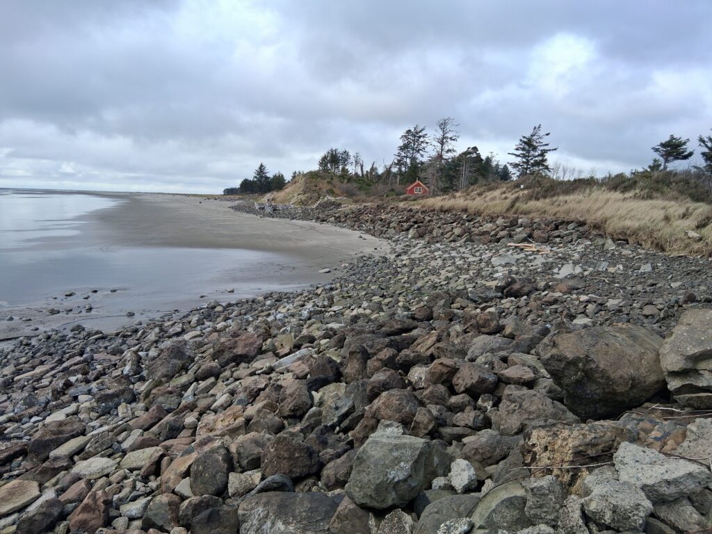 a rocky beach with a house in the distance (MyCoast AI)