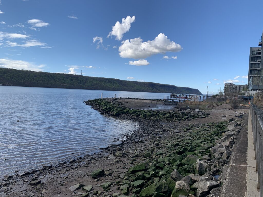 a rocky beach with a body of water and buildings on the side (MyCoast AI)