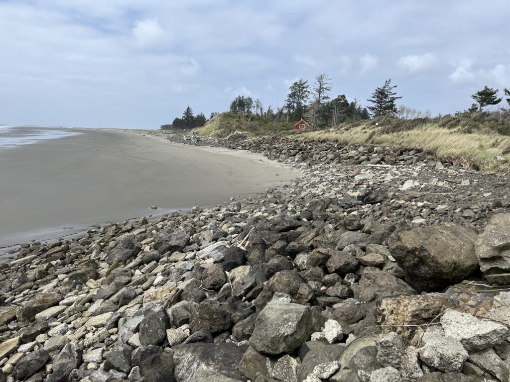 a rocky beach with a house in the distance (MyCoast AI)