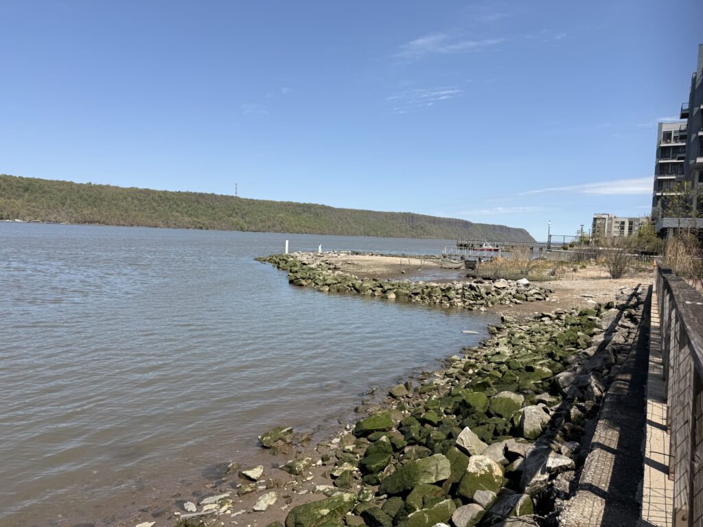 a rocky beach with a body of water and buildings on the side (MyCoast AI)