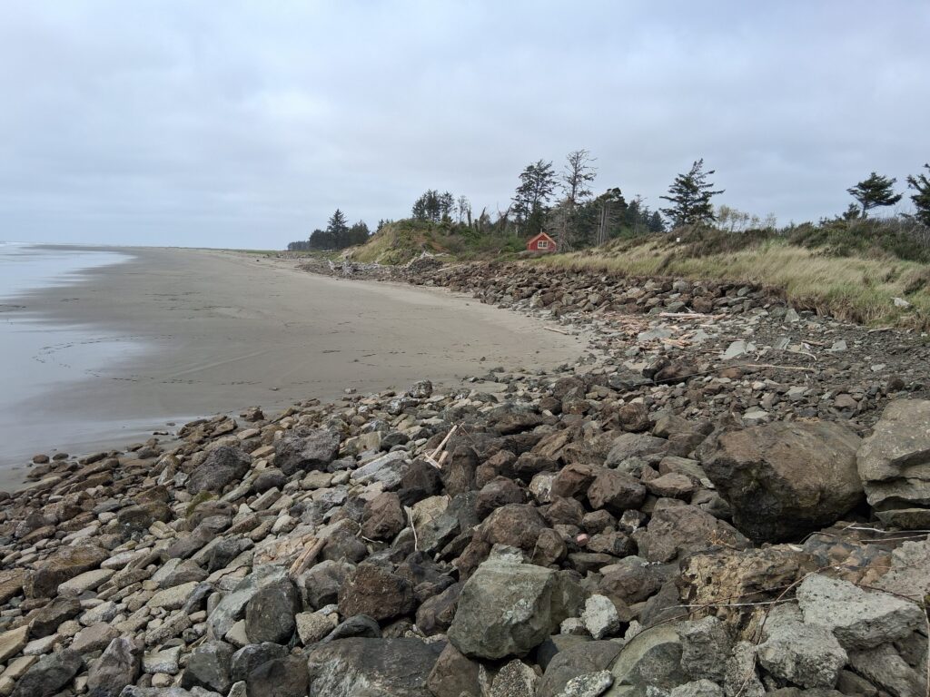 a rocky beach with a house in the distance (MyCoast AI)