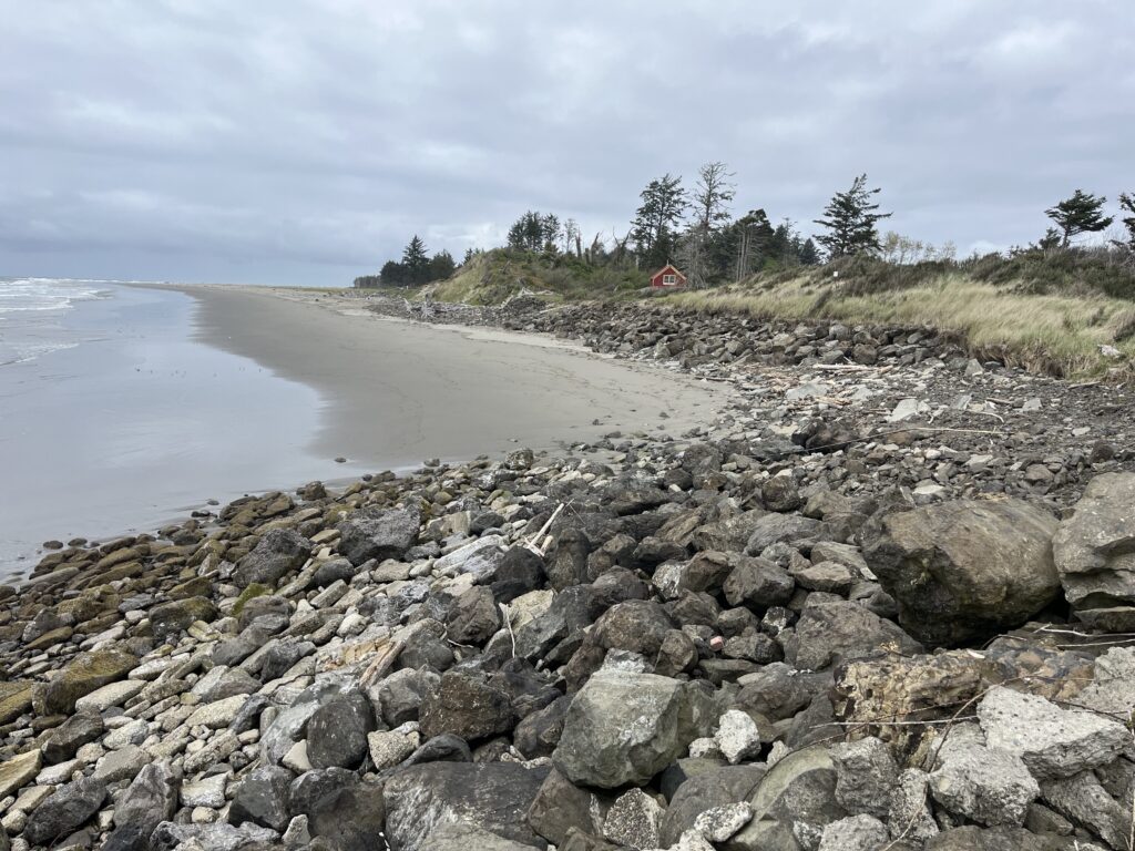 a rocky beach with a house in the distance (MyCoast AI)