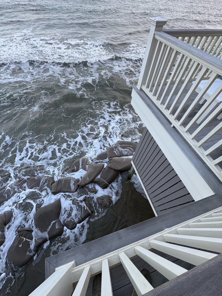 a deck with a railing and rocks by the water (MyCoast AI)