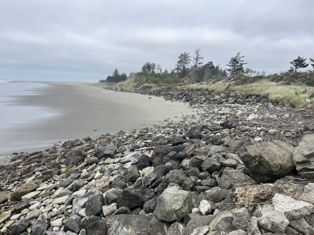 a rocky beach with a house in the distance (MyCoast AI)