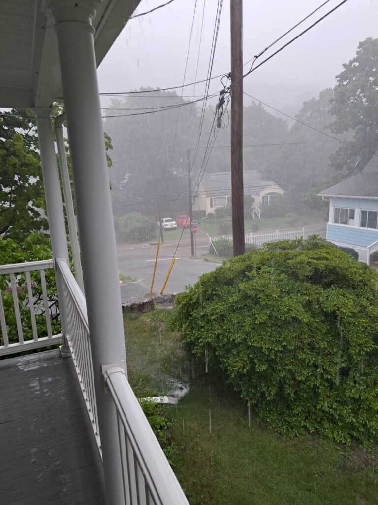 a view of a street through a window of a house and trees (MyCoast AI)